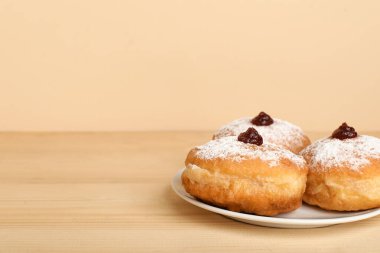 Hanuka kutlaması için lezzetli çöreklerle dolu tabaklar ahşap masada renk arka planına karşı.
