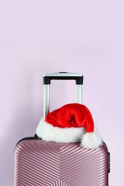 Renkli arka planda Noel Baba şapkası olan şık bavul, yakın plan.