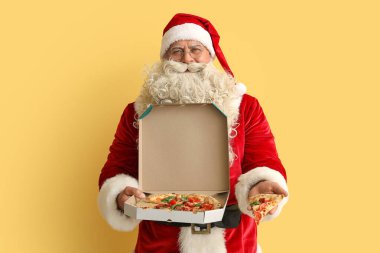 Sarı arka planda bir kutu lezzetli pizzayla Noel Baba
