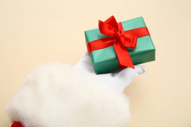 Bej arka planda yeşil hediye kutusu olan Noel Baba