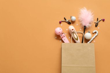 Farklı seks oyuncakları ve turuncu arka planda Noel dekoru olan bir alışveriş çantası.