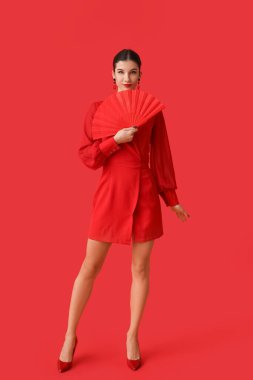 Kırmızı arka planda hayranı olan güzel genç bir kadın. Çin Yeni Yıl Kutlaması