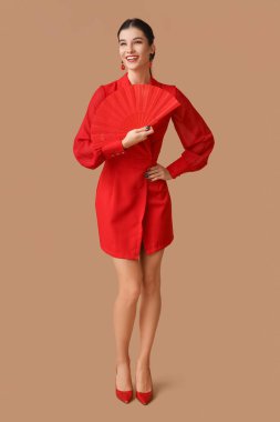 Kahverengi arka planda hayranı olan güzel, genç, mutlu bir kadın. Çin Yeni Yıl Kutlaması