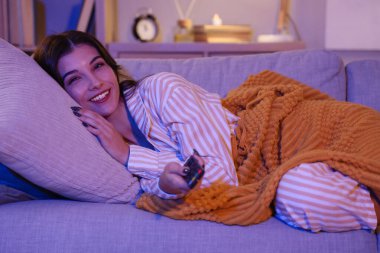 Akşam evde televizyon izleyen genç bir kadın.