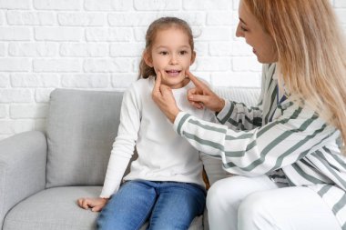 Ofiste küçük bir kızla çalışan olgun bir konuşma terapisti.