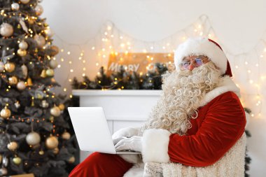 Noel Baba evde dizüstü bilgisayar kullanıyor.