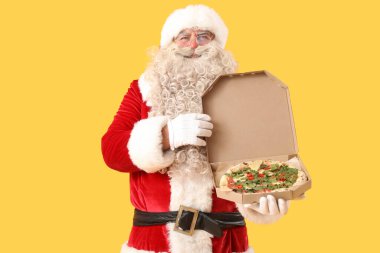 Sarı arka planda bir kutu lezzetli pizzayla Noel Baba