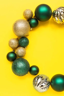 Sarı zemin üzerinde Noel ağacı toplarından yapılmış çerçeve