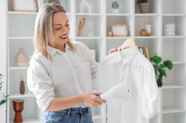 Evinde modern buharlı bir buharlı gömleği olan güzel bir kadın.