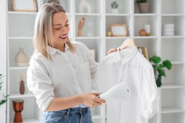 Evinde modern buharlı bir buharlı gömleği olan güzel bir kadın.