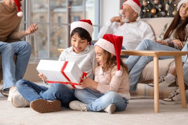 Noel Baba şapkalı küçük çocuklar ve aileleri evde.