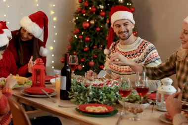 Genç bir adam akşam ailesiyle Noel yemeği yiyor.