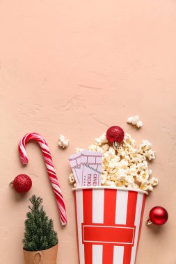 Bir kova patlamış mısır, sinema biletleri ve bej renkli grunge arka planda Noel dekoru.