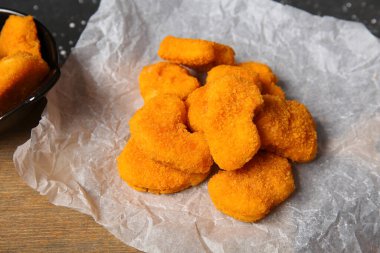 Siyah arka planda lezzetli nuggetları olan kağıt pişirme