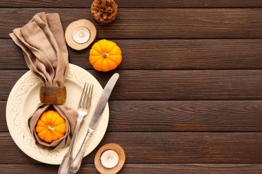 Balkabağı, koni ve ahşap zeminde yanan mumlarla sonbahar masası.