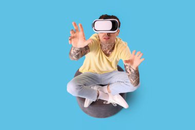Mavi arka planda VR gözlük kullanan genç adam, üst görünüm