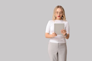 Gri arka planda modern tablet bilgisayarı olan güzel bir genç kadın.