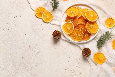 Beyaz arka planda kurumuş portakal dilimleri, kozalaklı ve köknar dalları.
