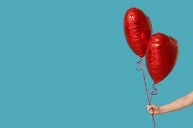 Mavi arka planda kalp şeklinde balonları olan bir kadın. Sevgililer Günü kutlaması