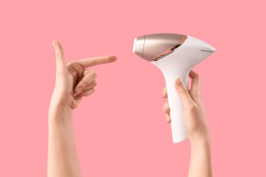 Pembe arka planda fotoepilatöre bakan kadın elleri