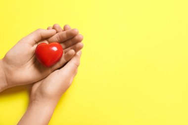 Sarı arka planda kırmızı kalpli kadın elleri
