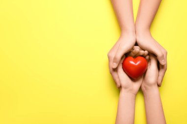 Sarı arka planda kırmızı kalpli kadın ve çocuğun elleri