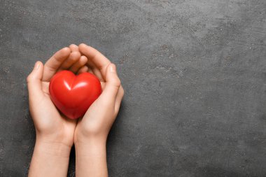 Siyah arka planda kırmızı kalpli kadın elleri