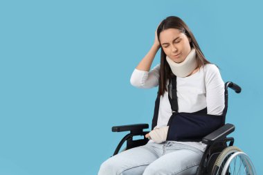 Injured young woman after accident in wheelchair on blue background clipart