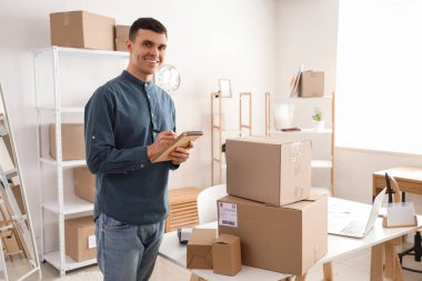 Depoda not defteri ve paket kutusu olan bir erkek çevrimiçi mağaza satıcısı.
