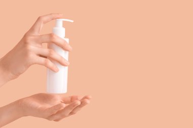 Renkli arka planda krem şişesi olan kadın elleri, yakın plan.