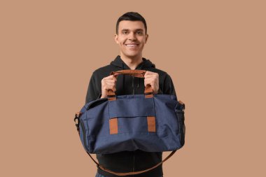 Bej arka planda spor çantalı genç bir adam.