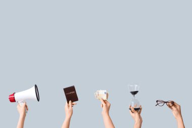 Kum saati, megafon, hukuk kitabı ve gri arka planda para tutan kadın elleri.