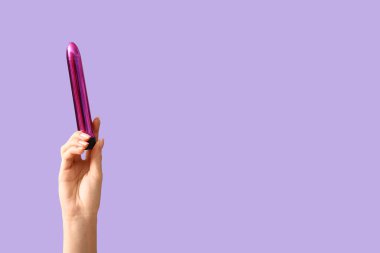 Leylak arka planında vibratörü olan kadın el, yakın plan.