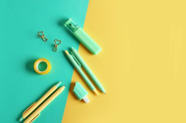Renkli arka planda kalemler, cilt klipleri ve selobant