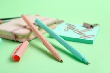 Yeşil arkaplanda defter olan kalemler