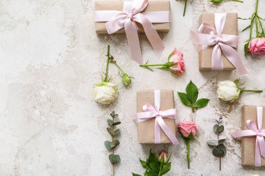 Güllü çiçek kompozisyonu ve açık arkaplanda paketlenmiş güzel hediye kutuları.