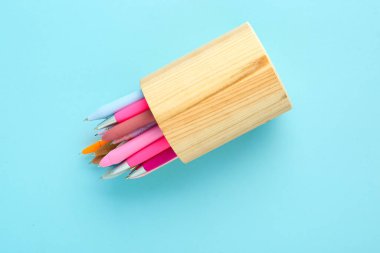 Mavi arka planda farklı kalemleri olan tahta tutucu