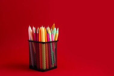 Kırmızı arkaplanda farklı kalemlerle tutucu