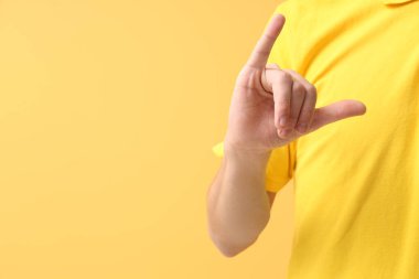 Sarı arka planda işaret dili kullanan genç sağır adam, yakın plan.