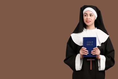 Kahverengi arka planda İncil 'i olan genç rahibenin portresi