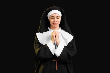 Siyah arka planda dua eden genç bir rahibe