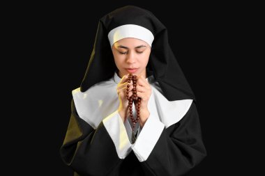 Siyah arka planda dua eden genç bir rahibe