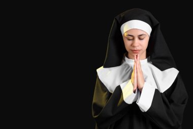 Siyah arka planda dua eden genç bir rahibe