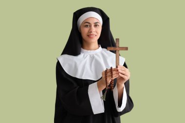 Yeşil arka planda haçlı ve boncuklu genç rahibe.