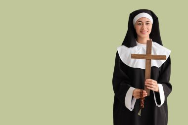 Yeşil arka planda haçlı ve boncuklu genç rahibe.