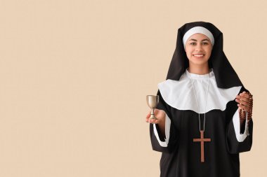 Bej arka planda tespih ve kadehli genç rahibe.