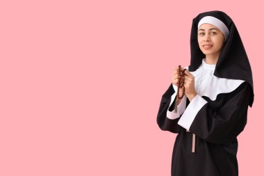 Pembe arka planda dua eden boncuklu genç rahibe.