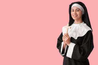 Pembe arka planda haç çizen genç rahibe