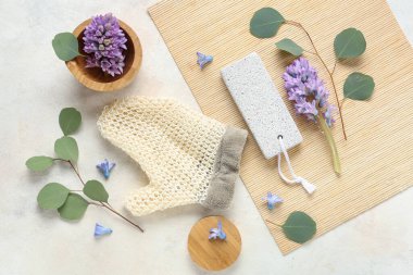 Hafif arkaplanda spa malzemeleri, çiçekler ve okaliptüs dallarıyla kompozisyon