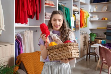 Atölyede bir sepet örgü ipliği olan genç bir kadın.